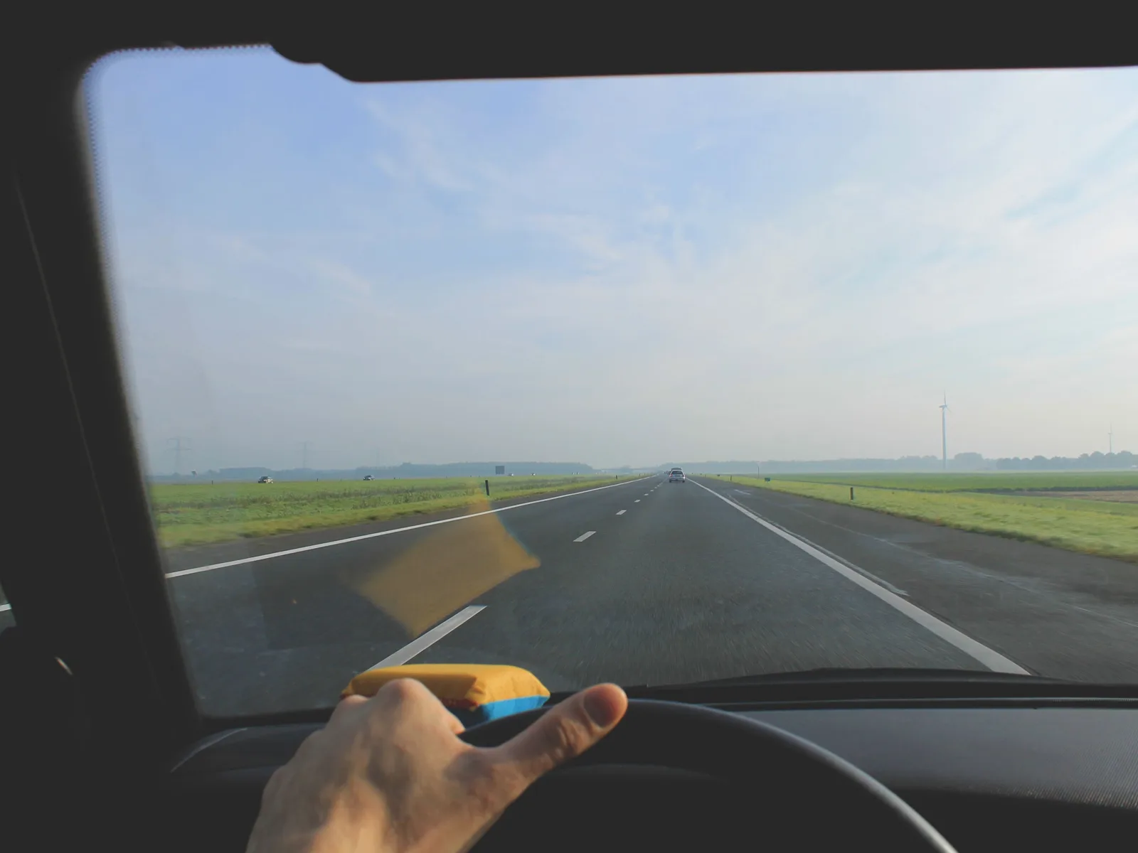 Vue du conducteur sur une route de campagne au volant, mains sur le volant.